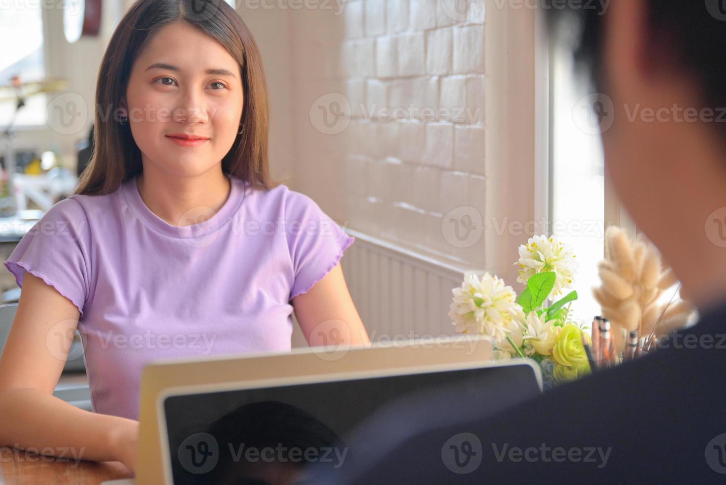 jonge vrouwelijke student keek naar een vriend die tegenover zat. ze leren thuis online met een laptop. foto