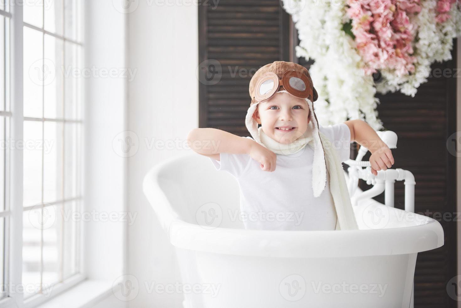 gelukkig kind in piloothoed spelen in de badkamer. jeugd. fantasie, verbeelding. foto