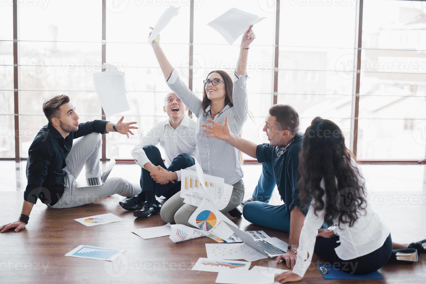 jonge creatieve mensen in moderne kantoren. groep jonge zakenmensen werken samen met laptop. freelancers zittend op de vloer. samenwerking corporate prestatie. teamwork concept foto