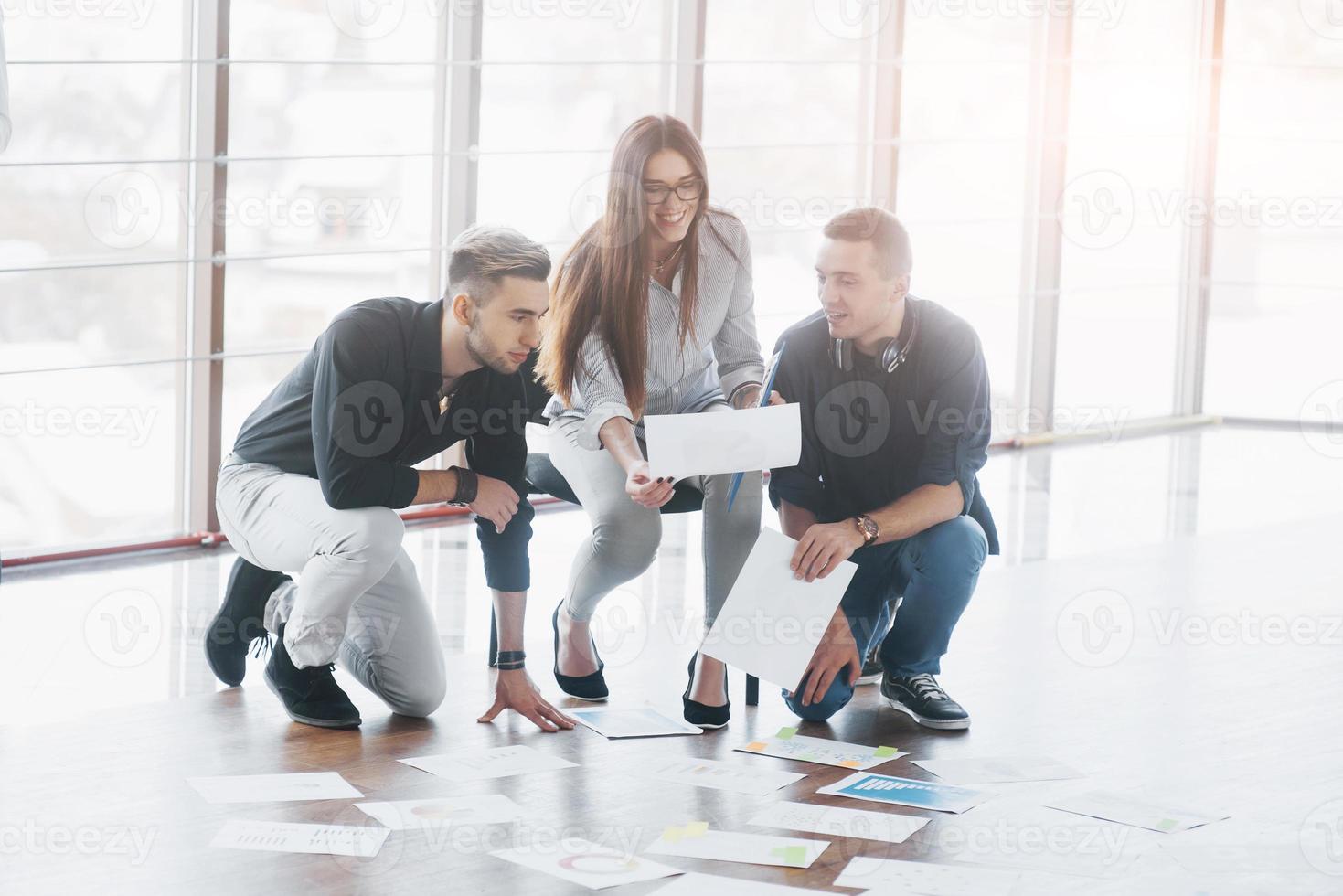 jonge creatieve mensen in moderne kantoren. groep jonge zakenmensen werken samen met laptop. freelancers zittend op de vloer. samenwerking corporate prestatie. teamwork concept foto