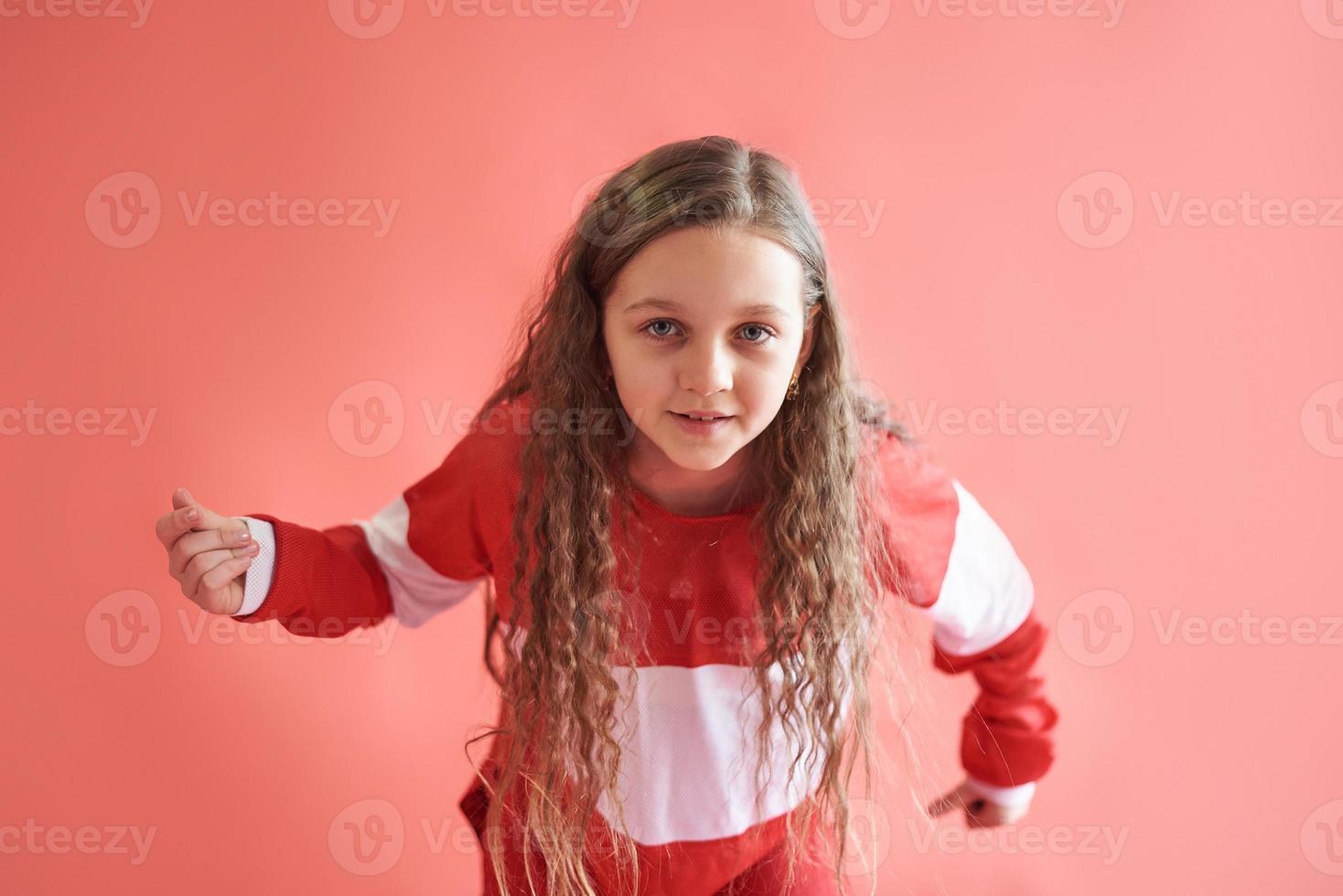 jong mooi schattig meisje dansen op rode achtergrond, moderne slanke hiphop-stijl tienermeisje springen foto