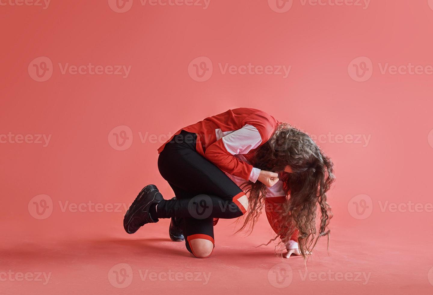 jong mooi schattig meisje dansen op rode achtergrond, moderne slanke hiphop-stijl tienermeisje springen foto