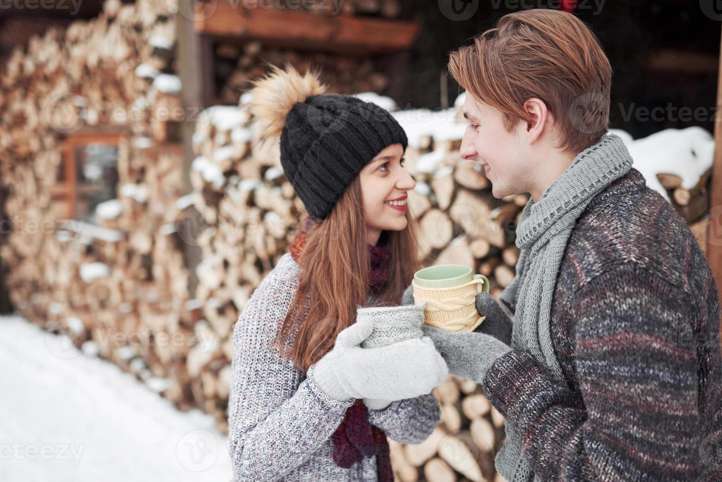 foto van gelukkige man en mooie vrouw met kopjes buiten in de winter. wintervakantie en vakantie. kerst paar gelukkige man en vrouw drinken warme wijn. verliefd stel