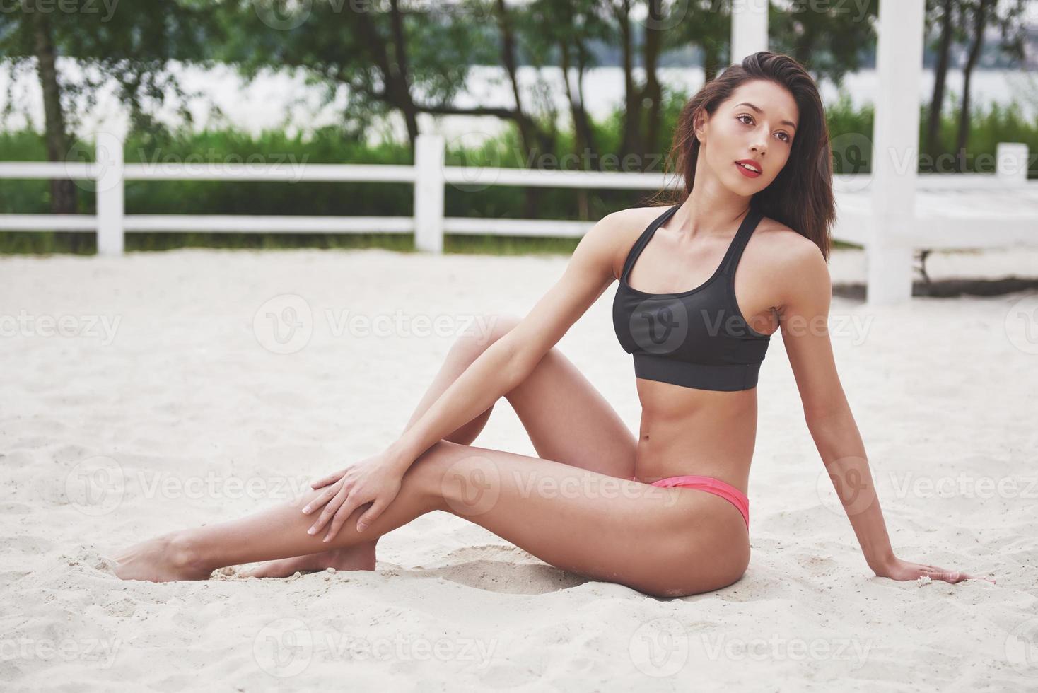 mooi slank luxe meisje in bikini op het zandstrand op een tropisch eiland. sexy gebruind lichaam en perfect figuur foto