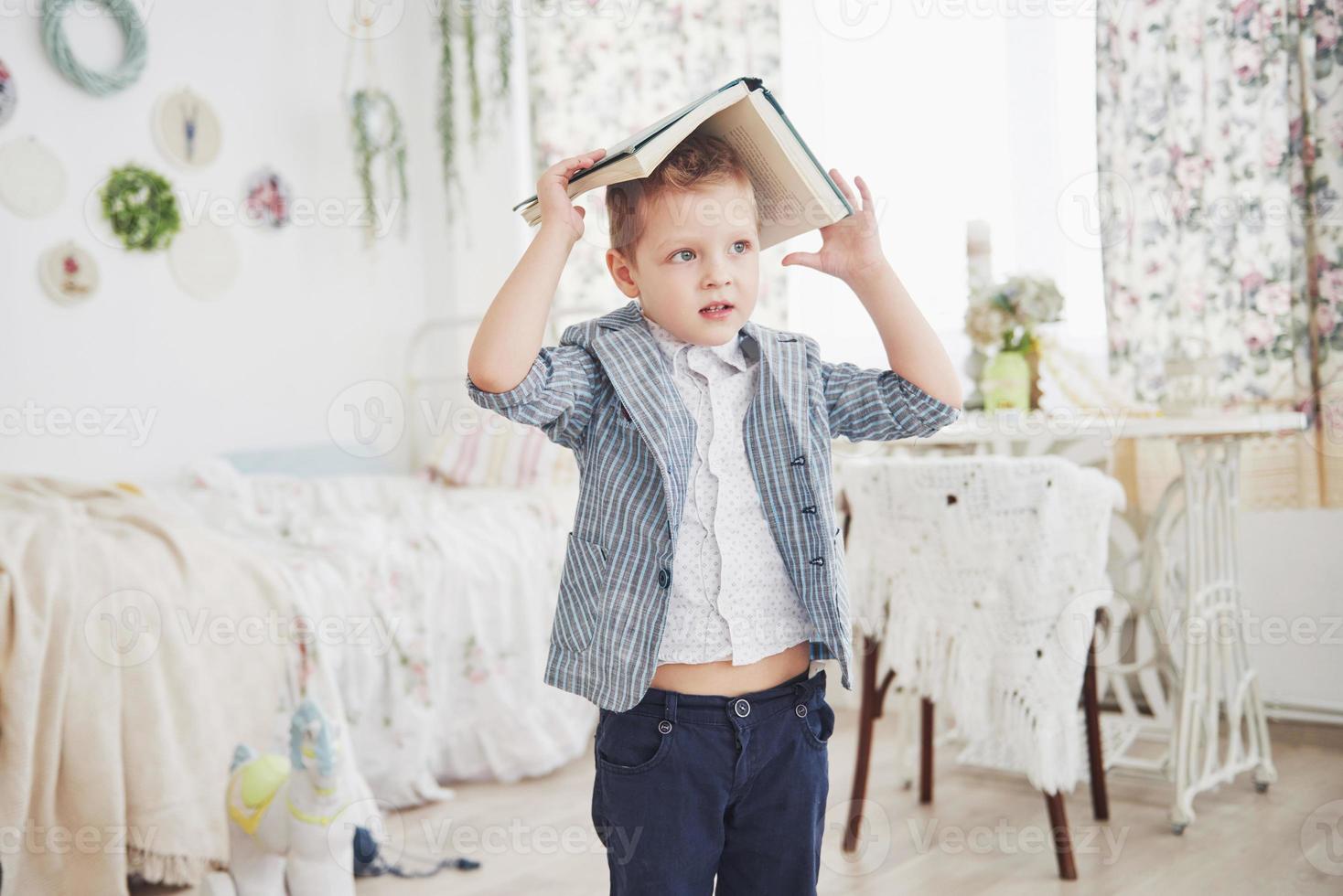 foto van ijverige schooljongen met boek op zijn hoofd huiswerk maken. de schooljongen is het huiswerk beu