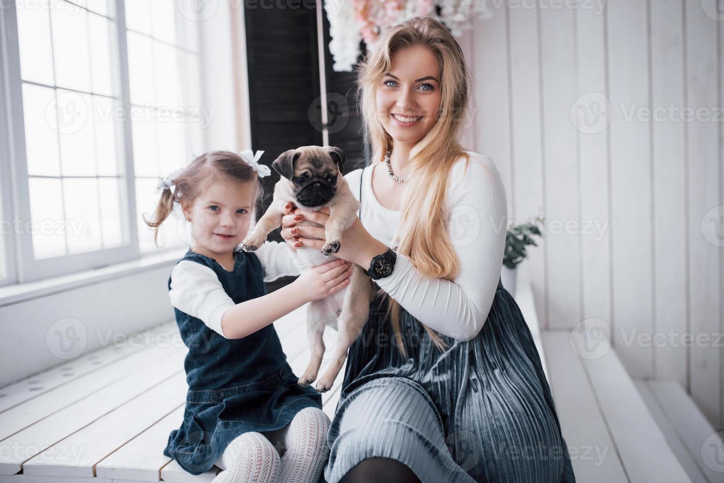 gelukkige liefdevolle familie. moeder en haar dochter kind meisje spelen en knuffelen schattige pug foto