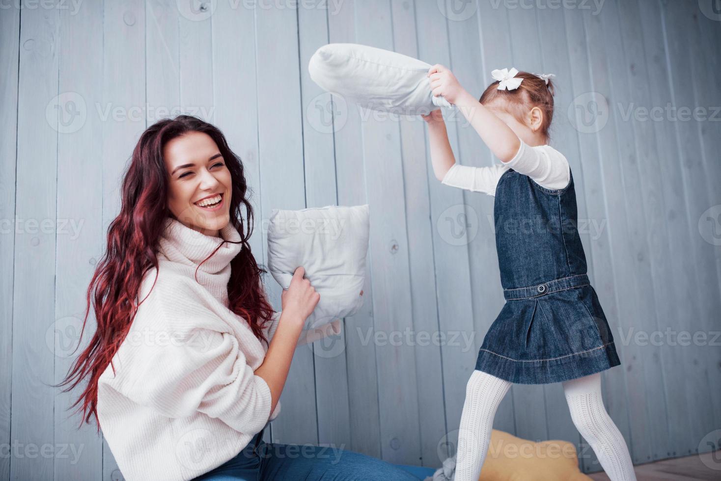 gelukkige familie de moeder en haar kindmeisje vechten kussens. gelukkige familie spelletjes foto