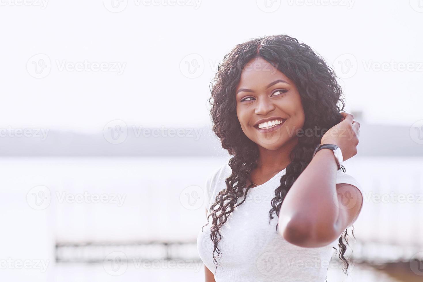 portret van lachende jonge zwarte vrouw met zonlicht flare foto