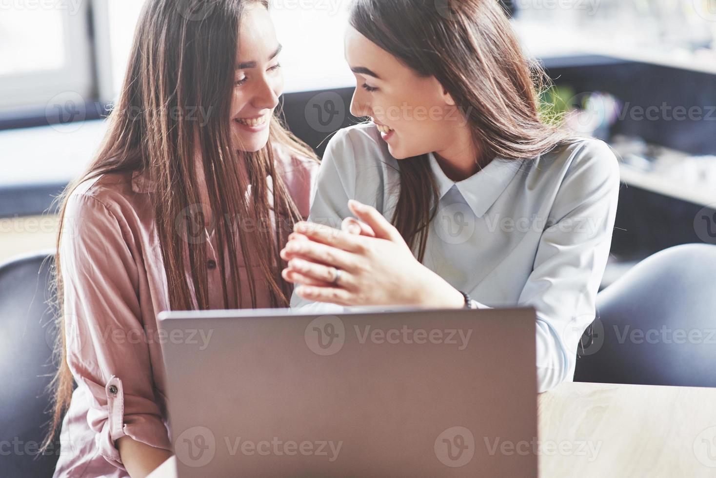 twee mooie tweelingmeisjes brengen 's ochtends tijd door in de bibliotheek. zussen die samen studeren en glimlachen foto