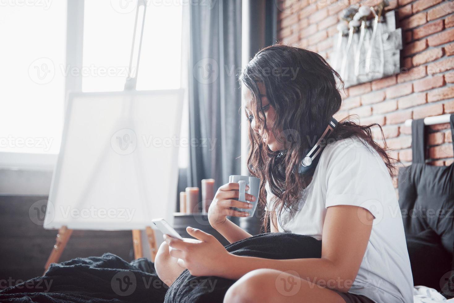 gelukkig mooi Afrikaans meisje in nachtkleding die zich uitstrekt glimlachend zittend op bed thuis werd 's ochtends wakker op een zonnige dag foto