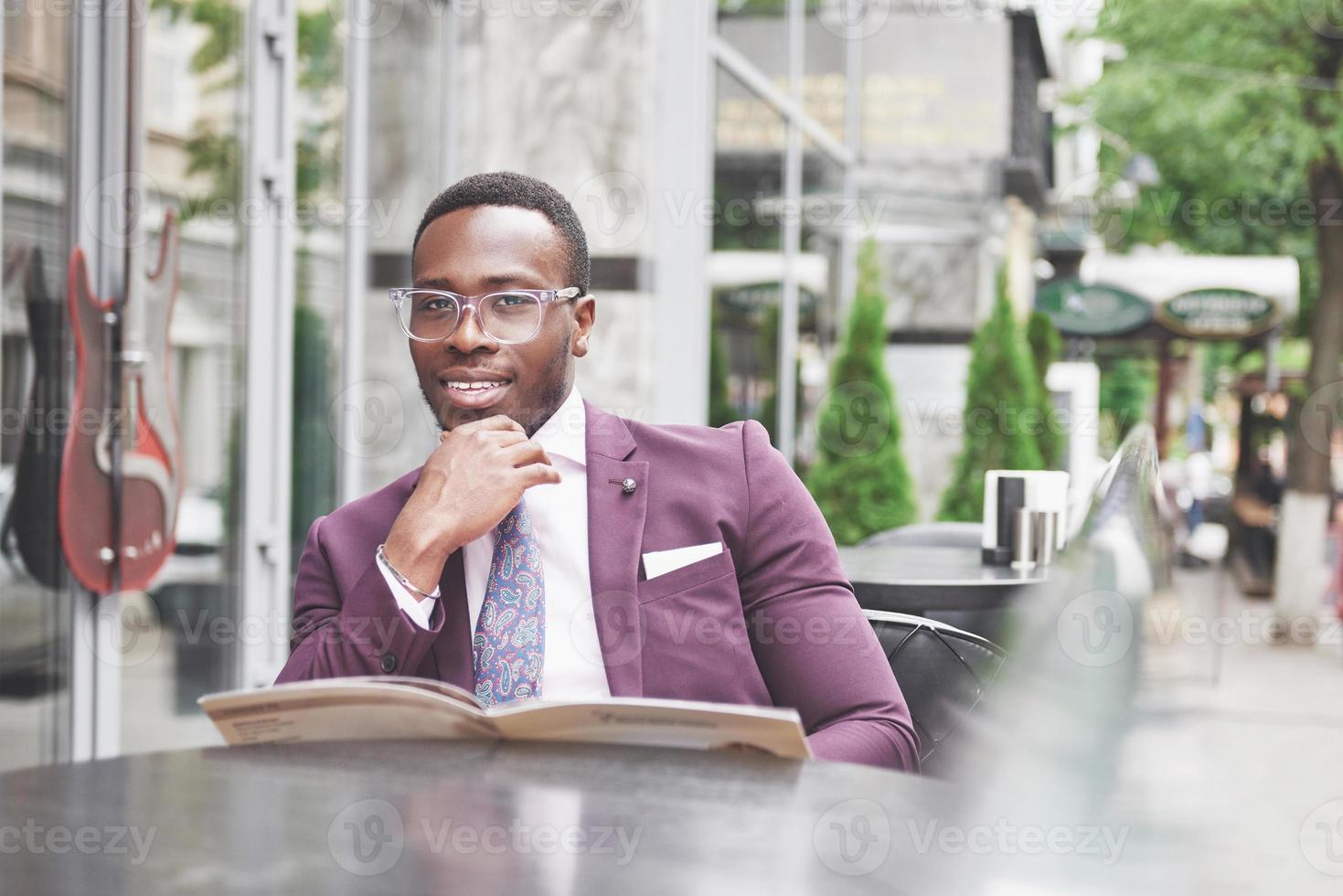 een mooie Afro-Amerikaanse zakenman leest een menu in een café foto