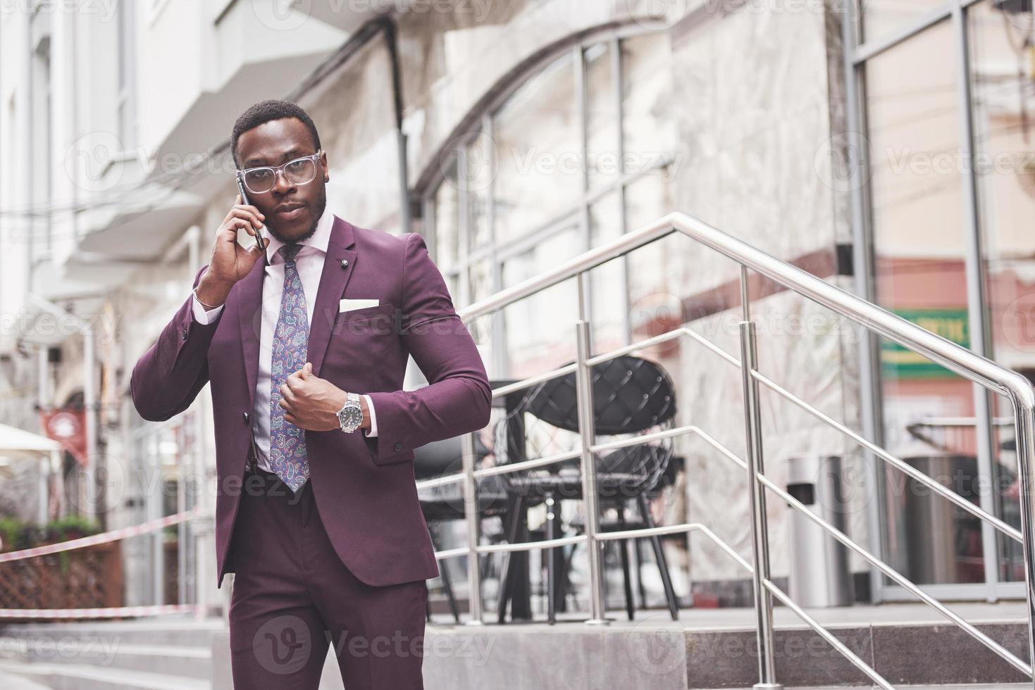 portret van een jonge en knappe Afro-Amerikaanse zakenman die in een pak aan de telefoon praat foto