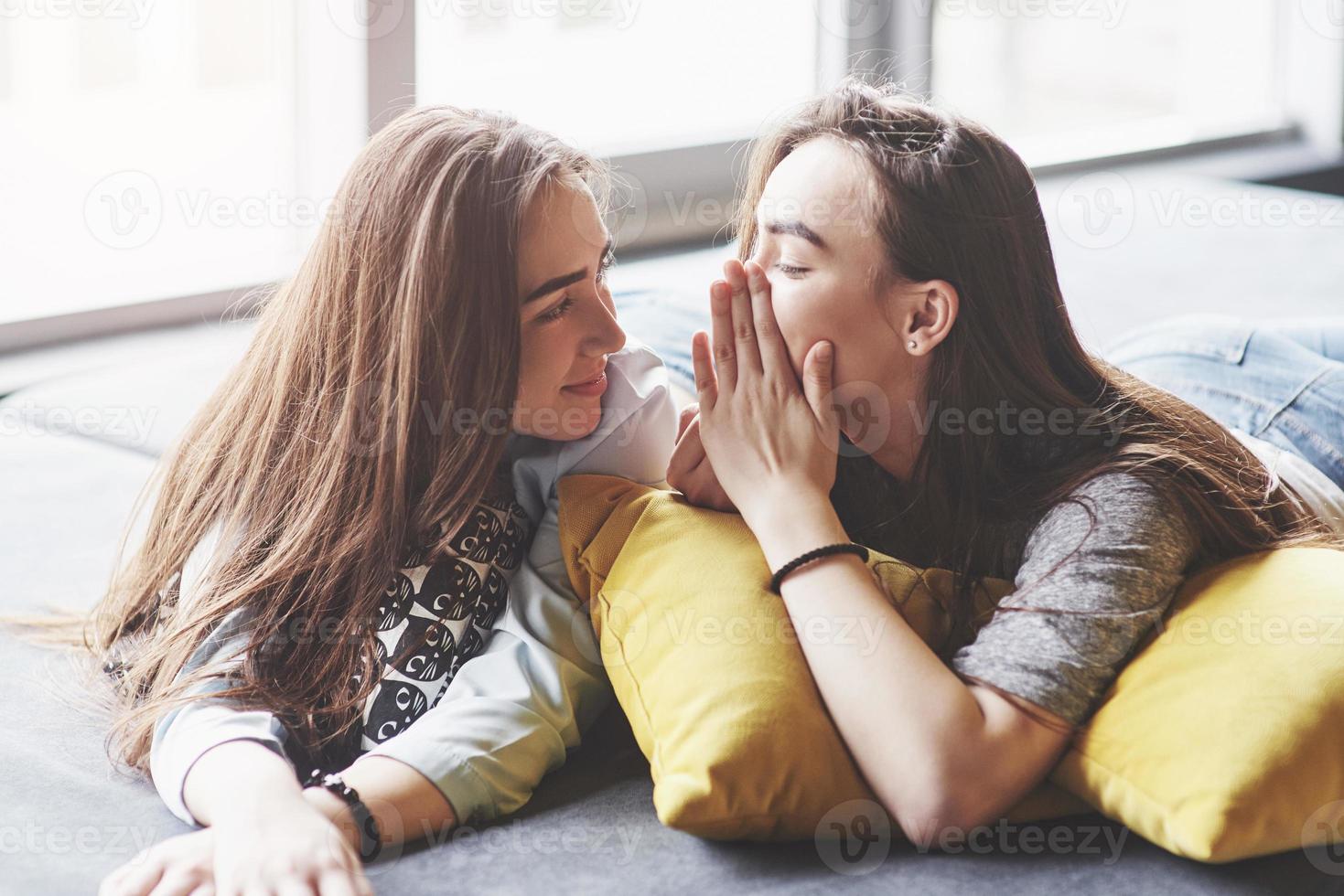 twee mooie jonge tweelingzusjes die tijd doorbrengen samen met kussens. broers en zussen met plezier thuis concept foto