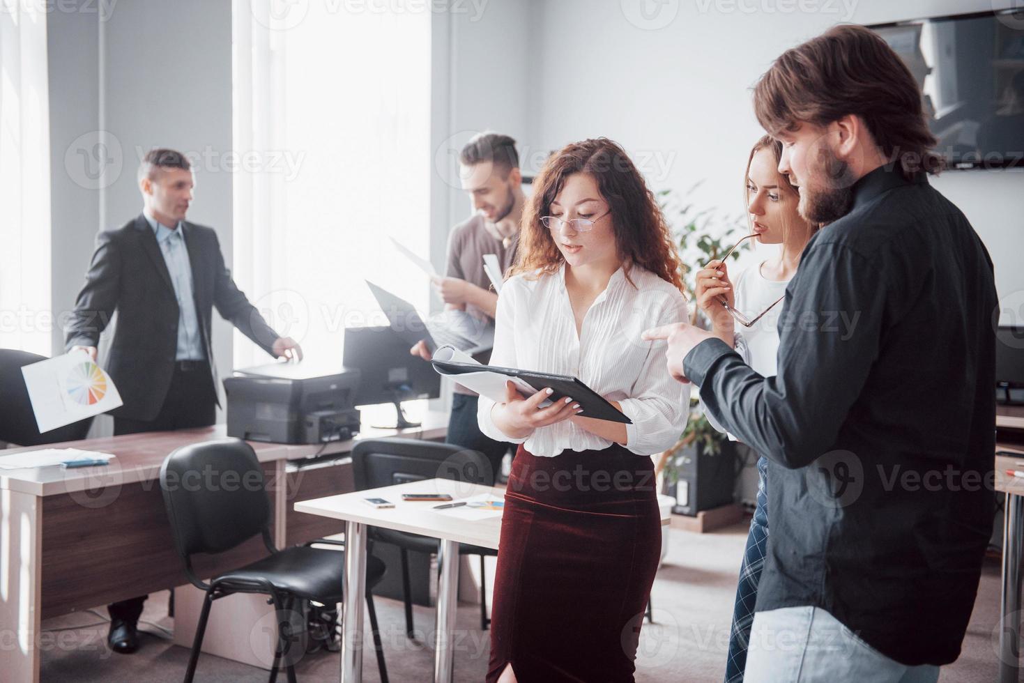 een groep jonge collega's praat over werkproblemen in moderne kantoorruimte. foto