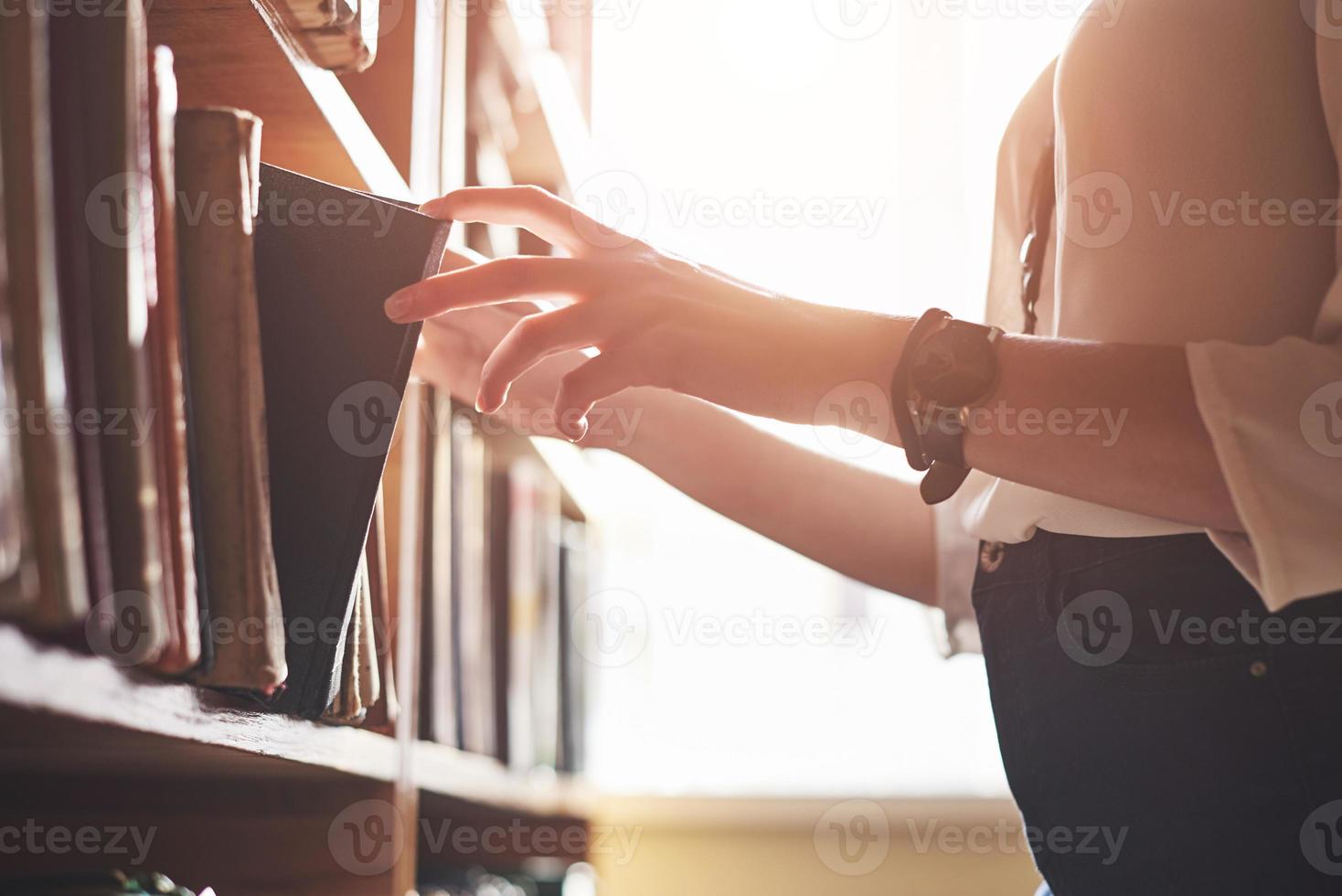 een jonge studente op zoek naar literatuur in de buurt van de boekenplanken in de oude bibliotheek foto