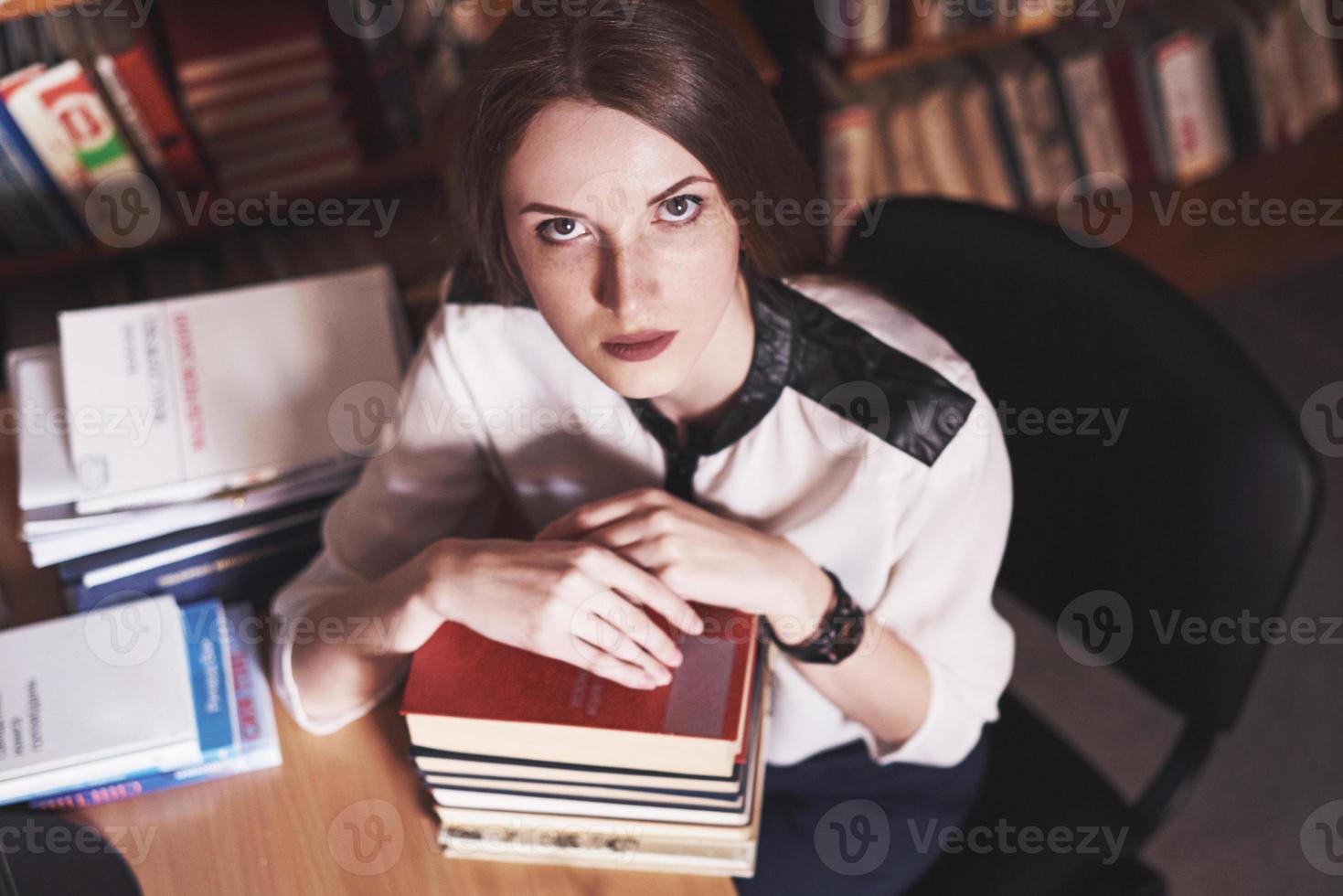 een jonge studente is moe in de leeszaal van de oude bibliotheek foto