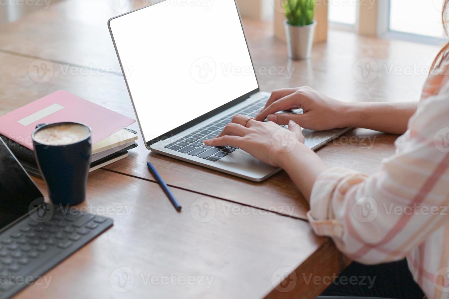 vergrote weergave van zakenvrouw hand gebruikt een laptop op een tafel met koffie in het comfortabele kantoor. foto