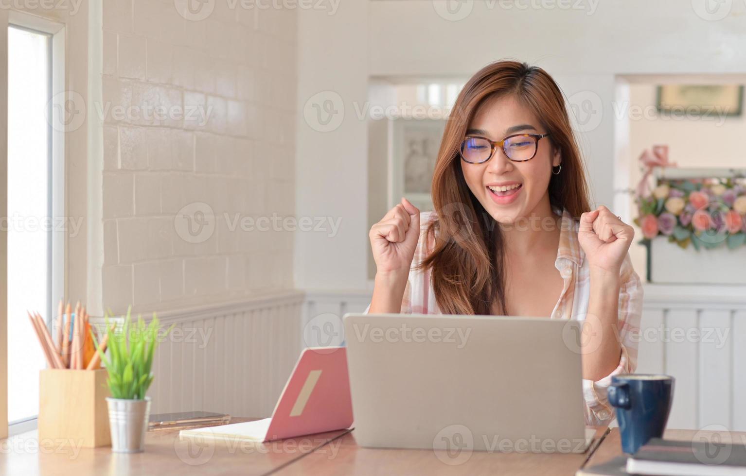 vrouwelijke tienerstudenten steken gelukkige handen op terwijl ze thuis online studeren met een laptop. foto