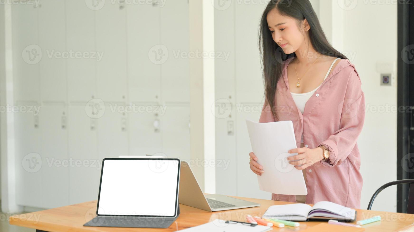 aziatische vrouw slaat documenten op een bureau op met een laptop in een eigentijds kantoor. foto