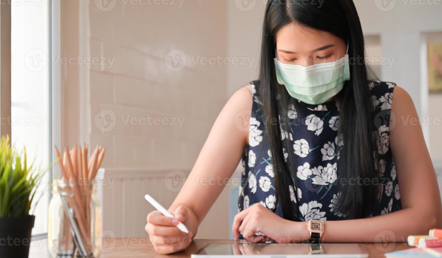 bijgesneden opname van jonge vrouwen en tablet die thuis werken. Ze is beschermd tegen de uitbraak van het coronavirus. foto