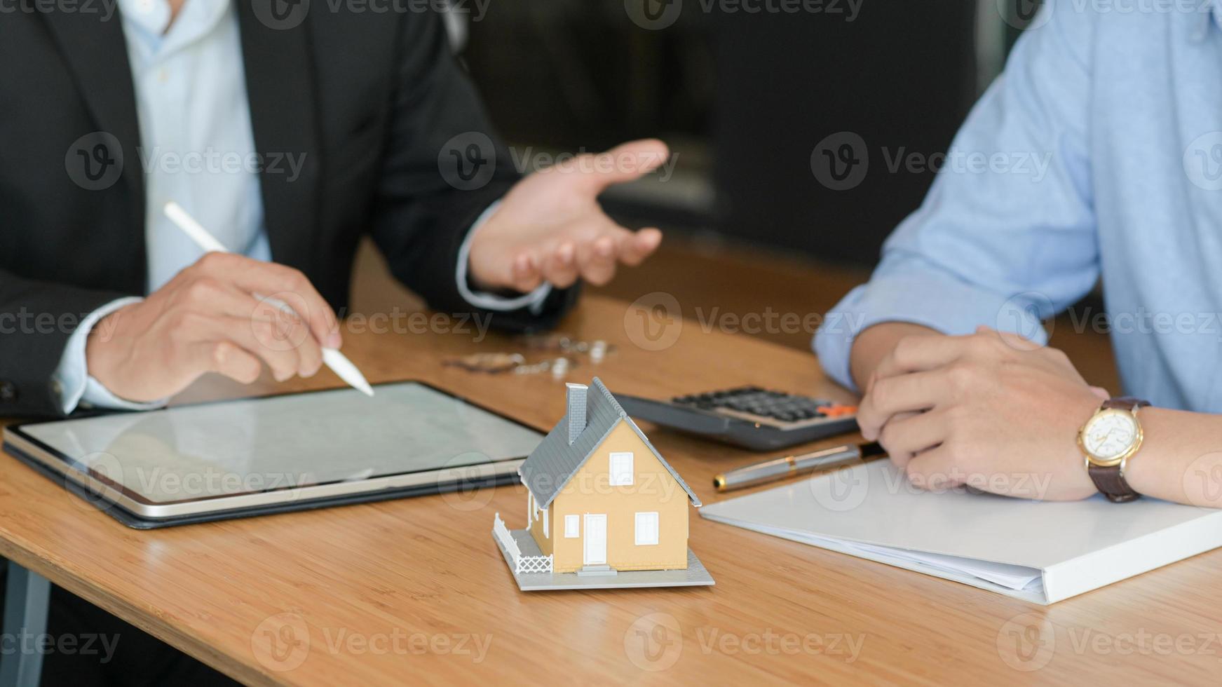 klanten luisteren naar aanbiedingen van thuismakelaars. met modelwoningen en tablet op tafel. foto