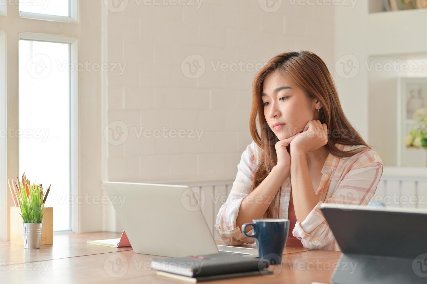 Aziatische vrouwelijke student aandachtig de laptop lezen. ze bereidt zich voor op het examen om af te studeren. foto