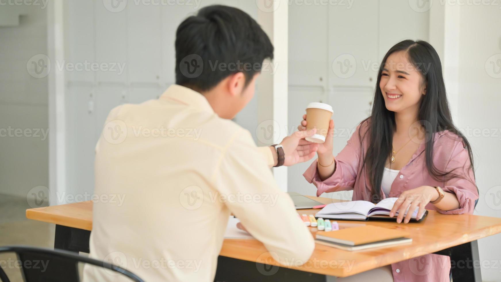 shot van mannen die koffie geven aan vrouwen terwijl ze gestrest zijn door boeken te lezen voor examenvoorbereiding. foto