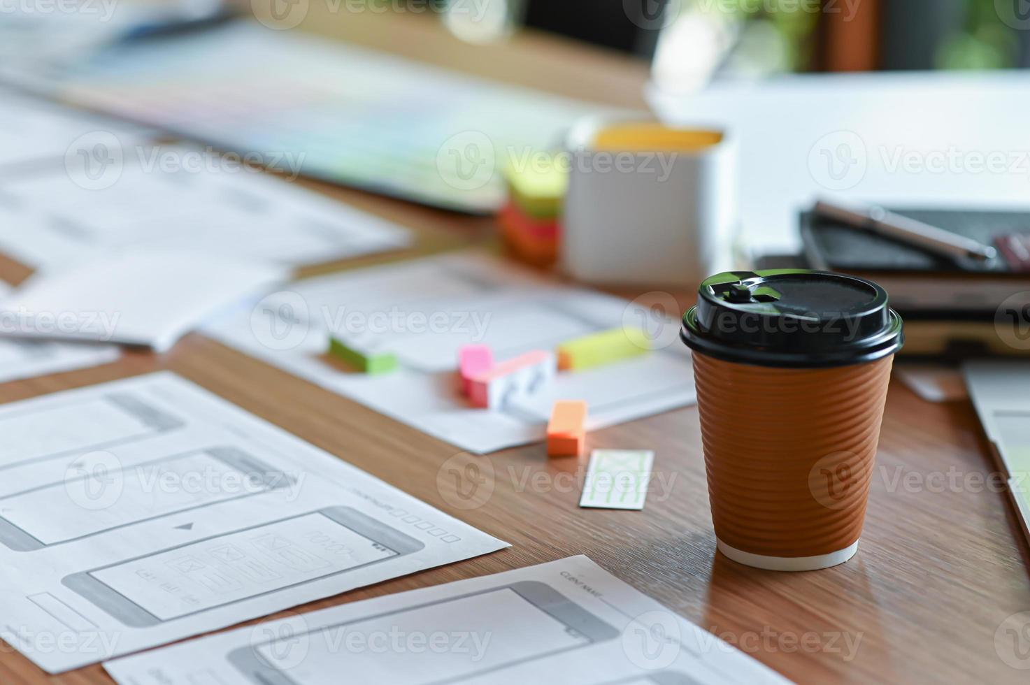 bijgesneden opname van een applicatieontwerpbureau met een schets van een mobiel scherm en koffie om mee te nemen in het thuiskantoor. foto