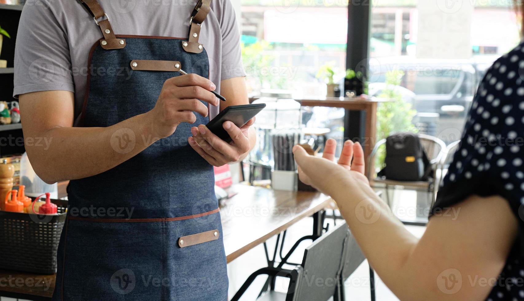 werknemer die een smartphone vasthoudt om het menu van de klantorder op te slaan. foto