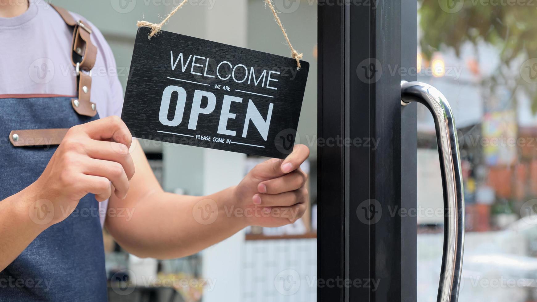 bijgesneden opname van bedrijfseigenaren die een open bord houden om service te verlenen. foto