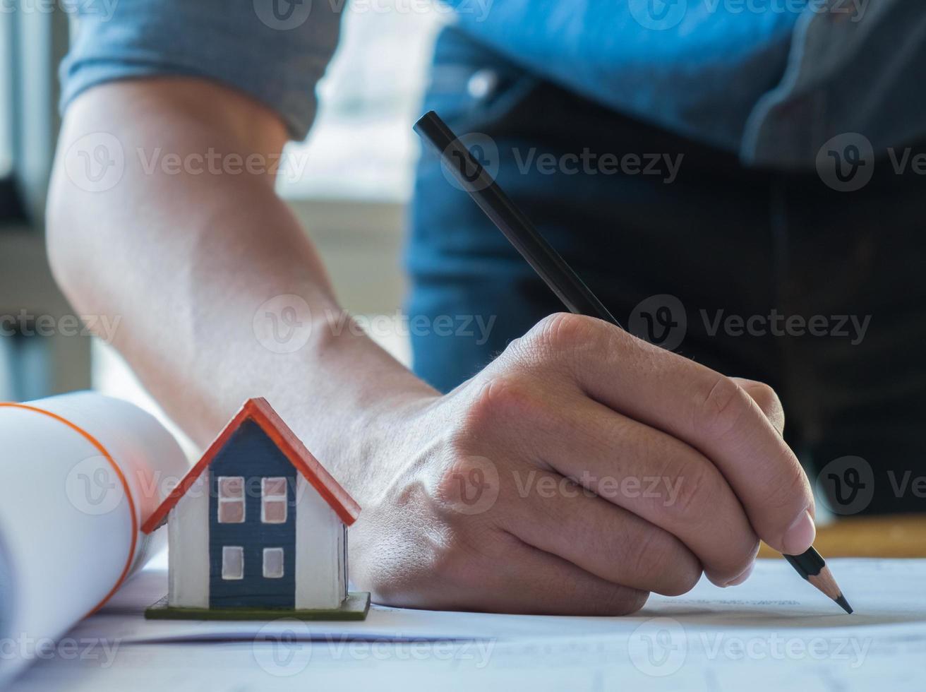 huisontwerpideeën, jonge architect die een zwart potlood gebruikt om het huisplan te schetsen. foto