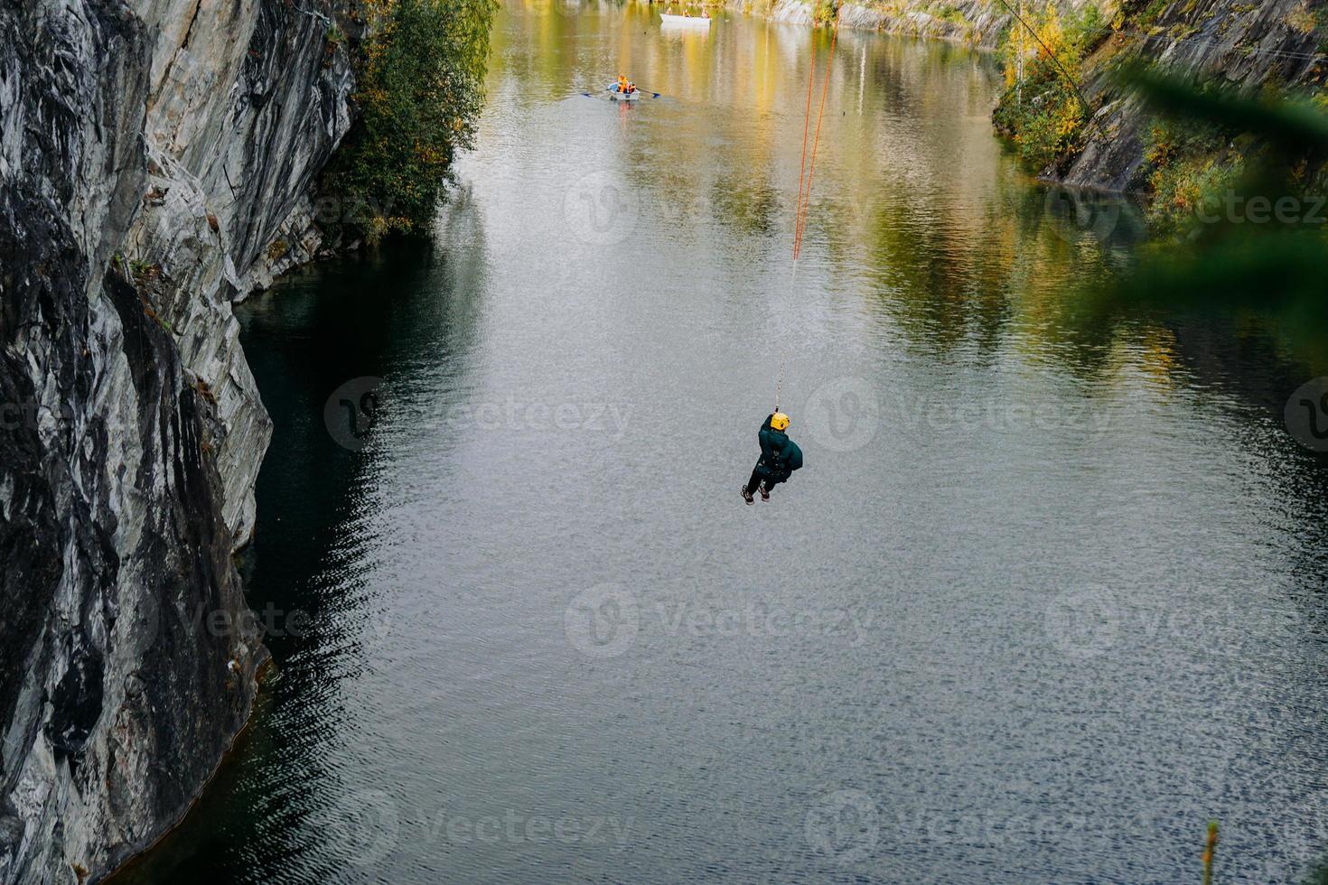 een man die uit een bungee springt over een kloof in het ruskeala-bergpark foto