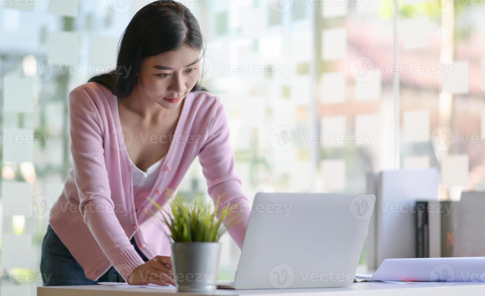 vrouwelijke student die een laptop gebruikt om een afstudeerproject te voltooien. Ze werkt thuis dat modern en comfortabel is. foto