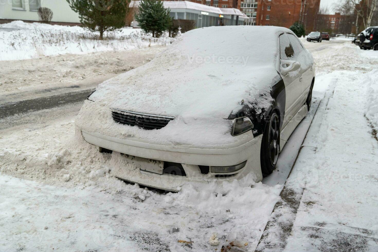 stad straat in winter met een auto begraven in sneeuw na sneeuw verwijdering foto