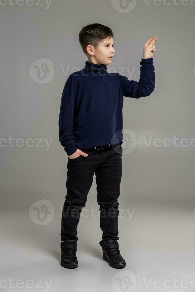 mooi hoor schooljongen is poseren Bij studio over- een grijs achtergrond. foto