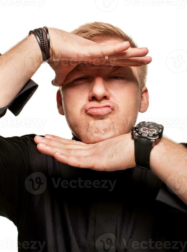 jong blond Mens in een zwart shirt, horloges en armband is maken gezichten, geïsoleerd Aan een wit achtergrond foto