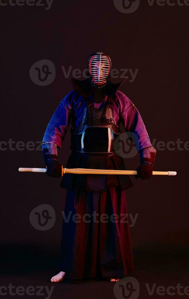 dichtbij omhoog schot, kendo vechter vervelend in een schild, traditioneel kimono, helm beoefenen krijgshaftig kunst met shinai bamboe zwaard, zwart achtergrond. foto