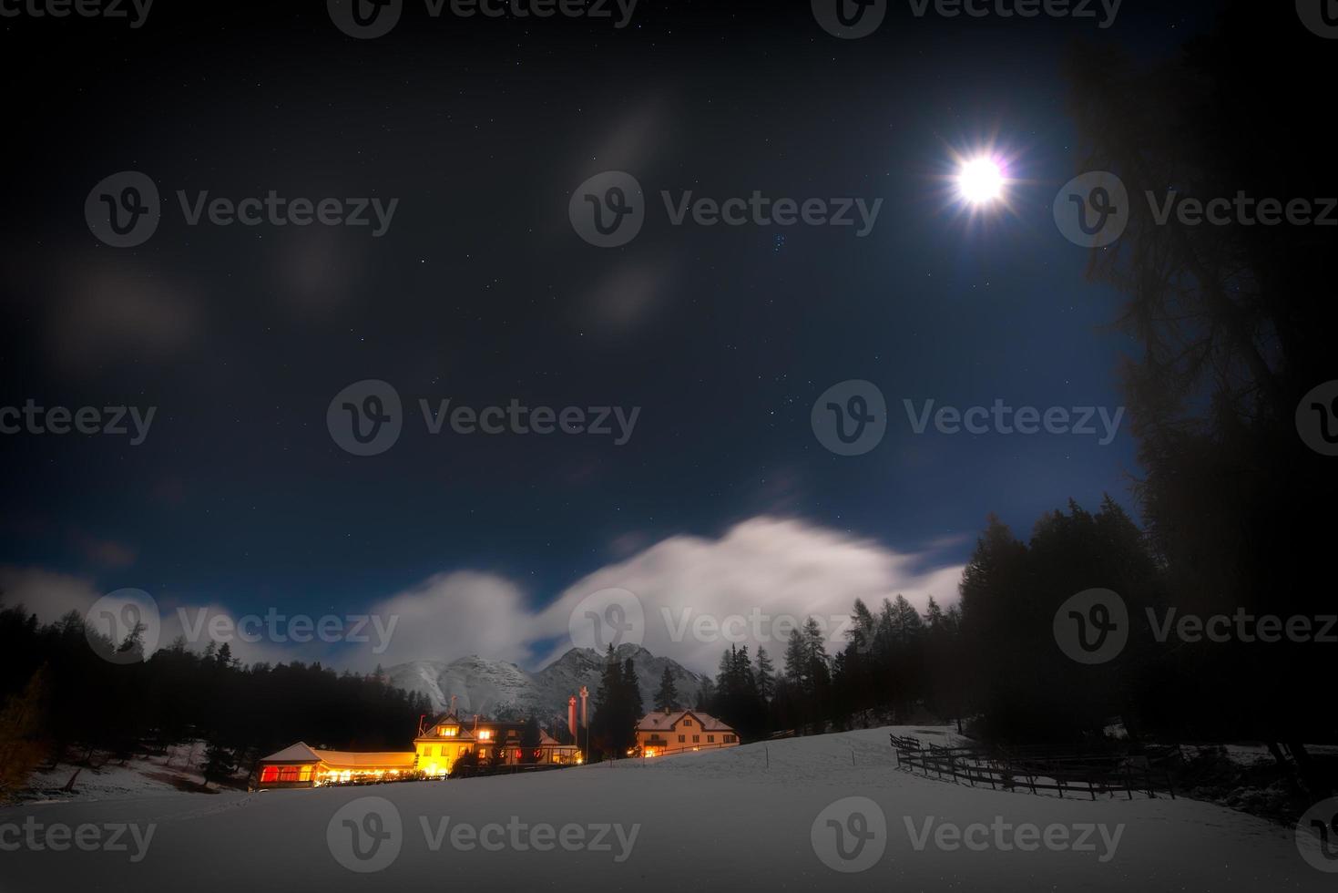 huizen in de sneeuw op een sterrennacht met de maan foto