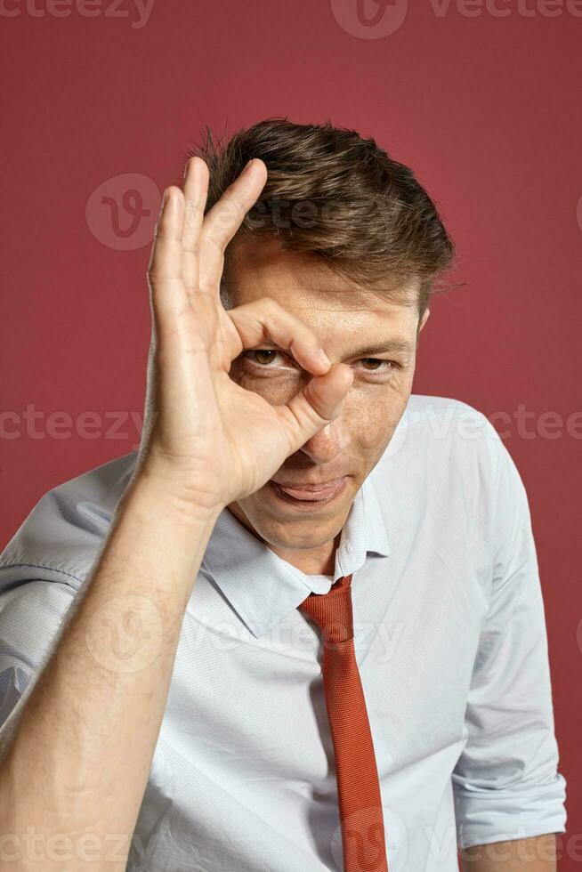 portret van een jong brunet Mens poseren in een studio tegen een rood achtergrond. foto