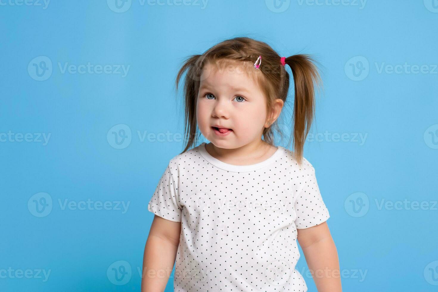 grappig kind in wit t-shirt Aan blauw achtergrond. weinig mooi meisje geïsoleerd Aan blauw achtergrond. kopiëren ruimte voor tekst. foto