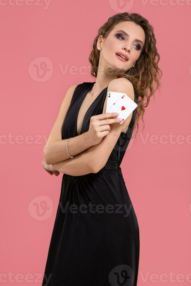 jong vrouw Holding twee azen in hand- tegen Aan roze achtergrond foto