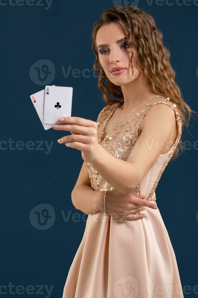 jong mooi vrouw Holding de winnend combinatie van poker kaarten Aan donker blauw achtergrond. twee azen foto