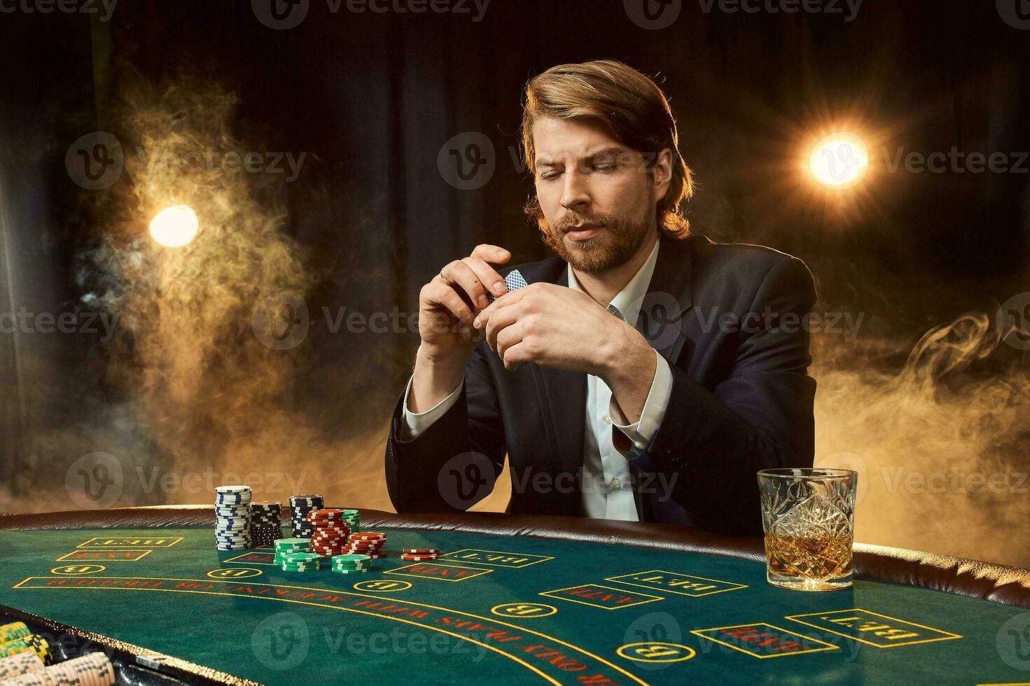 een Mens in een bedrijf pak zittend Bij de spel tafel. mannetje speler. passie, kaarten, chips, alcohol, Dobbelsteen, gokken, casino - het is net zo mannetje amusement. foto