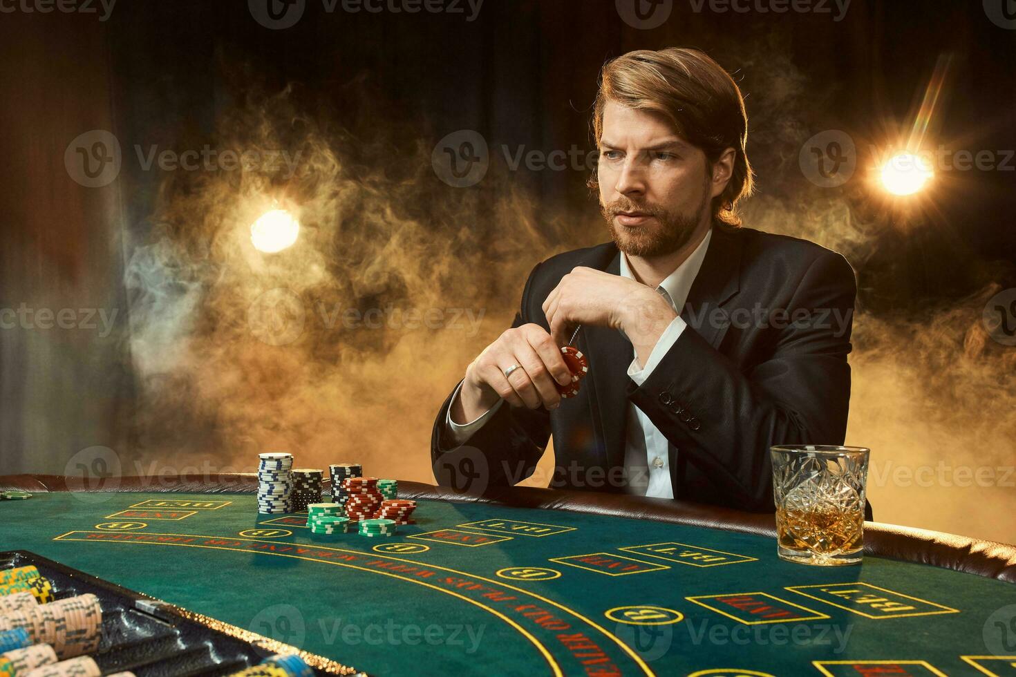 een Mens in een bedrijf pak zittend Bij de spel tafel. mannetje speler. passie, kaarten, chips, alcohol, Dobbelsteen, gokken, casino - het is net zo mannetje amusement. foto