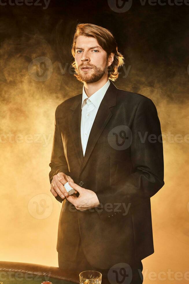 een Mens in een bedrijf pak staand in de buurt de spel tafel. mannetje speler. passie, kaarten, chips, alcohol, Dobbelsteen, gokken, casino - het is net zo mannetje amusement. foto