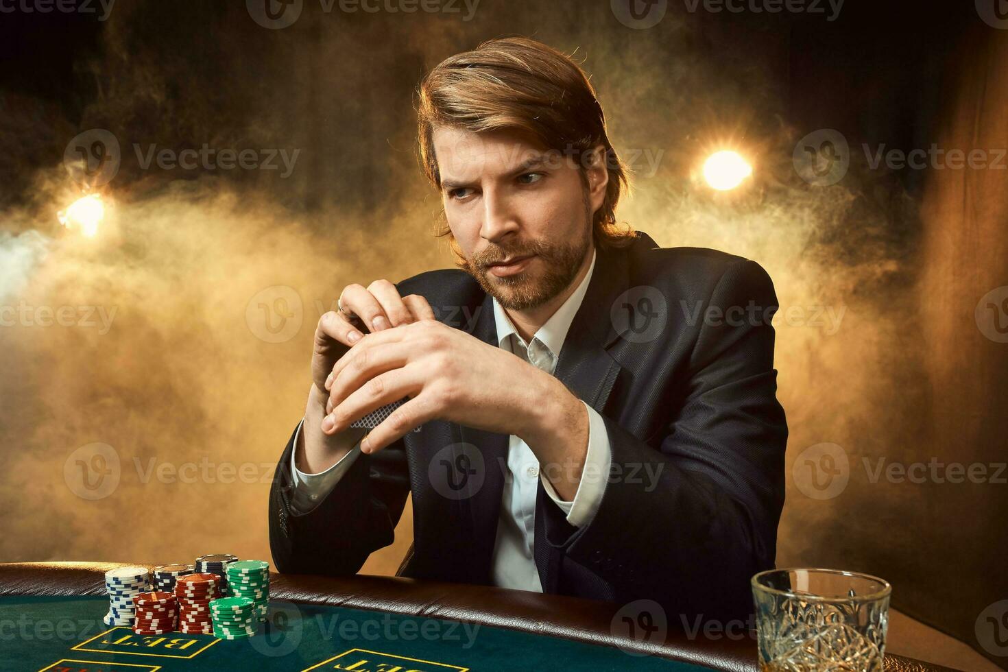 een Mens in een bedrijf pak zittend Bij de spel tafel. mannetje speler. passie, kaarten, chips, alcohol, Dobbelsteen, gokken, casino - het is net zo mannetje amusement. foto