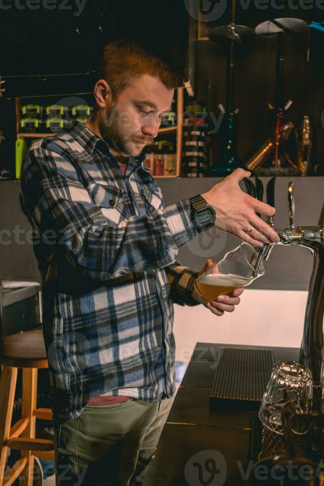 gebaard barman vulling glas met ongefilterd bier van kraan in kroeg foto