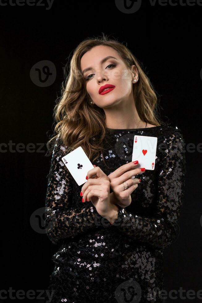 jong vrouw Holding spelen kaarten tegen een zwart achtergrond foto