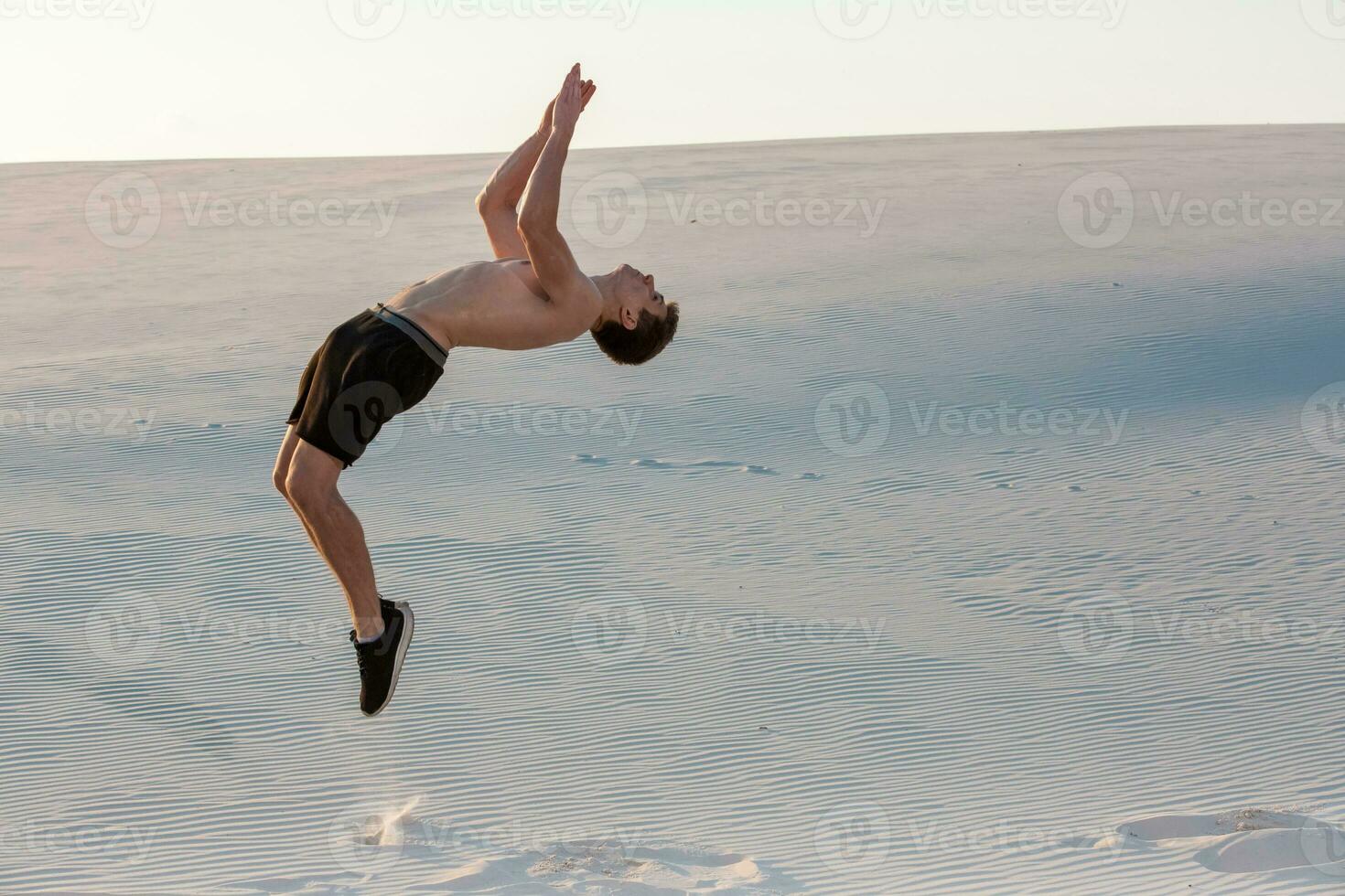 Mens studie parkour Aan hun eigen. acrobatiek in de zand foto