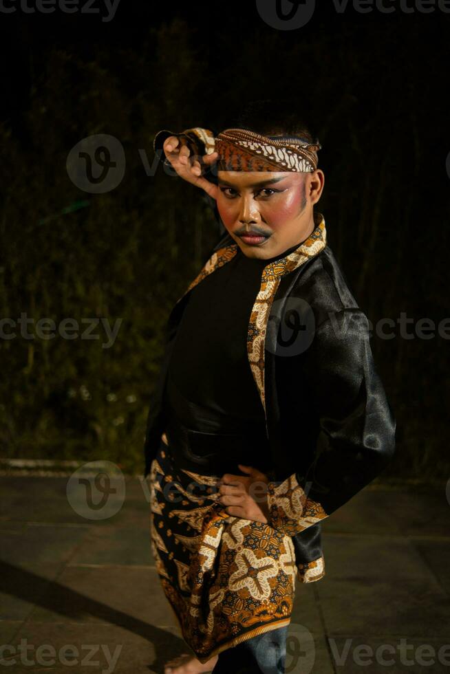 een mannetje danser vervelend een zwart kostuum vol van batik patronen met bedenken Aan zijn gezicht foto
